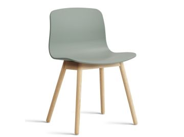 Der About A Chair AAC12 mit Standardgleiter (Herbstgrün) hat eine hellgrüne Sitzfläche und Holzbeine, die ein dänisches Designmöbel darstellen und vor einem weißen Hintergrund stehen.
