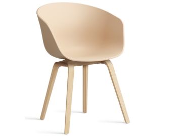 Der About A Chair AAC22 inkl.. Filzgleiter (pale beach) zeichnet sich durch einen modernen, beigefarbenen, gebogenen Kunststoffsitz und helle Holzbeine aus, inspiriert durch das ikonische Design von HAY, das vor einem weißen Hintergrund gezeigt wird.