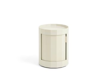 Der Facet Cabinet low (Eierschale) ist ein runder, cremefarbener Beistelltisch mit einem facettierten Design und einer kleinen vertikalen Tür - ein elegantes, vielseitiges Aufbewahrungsmöbel vor einem weißen Hintergrund.