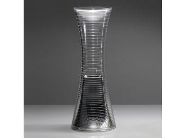 Eine hohe, klare Glasvase in Form einer Sanduhr mit horizontalen Rillen steht vor einem grauen Hintergrund - ihre elegante Form erinnert an die Come together (Aluminium) von Artemide.