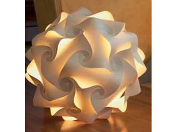 Das Sphere Lichtobjekt (Ø 47 cm) ist eine geometrische, leuchtend weiße Papierlampe mit wirbelnden, ineinandergreifenden Formen, die auf einer Holzoberfläche ruht - ein exquisites Beispiel für handgefertigte Leuchten.