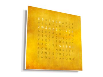 QLOCKTWO EARTH 45 CREATOR'S EDITION (CH) berndeutsch: Quadratische, orangefarbene Wanduhr aus goldfarbenem Edelstahl, die auf der Vorderseite in einem Raster mit schweizerdeutschen Wörtern versehen ist.