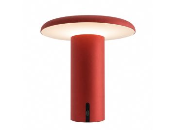 Die Takku Tischleuchte ist eine moderne, rote, kabellose Tischlampe von Artemide mit einem zylindrischen Sockel, einem breiten, flachen Schirm und einem dezenten schwarzen Einschaltknopf. Sie strahlt sanftes, weißes Licht aus und besticht durch ihr schlan
