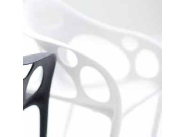 Nahaufnahme des Supernatural Armchair (weiß) von Moroso, entworfen von Ross Lovegrove, mit kreisförmigem Ausschnitt, einem schwarzen Stuhl im Vordergrund und einem unscharfen weißen Stuhl im Hintergrund.