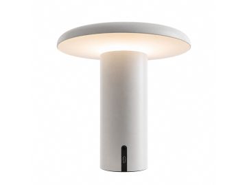 Die Takku Tischleuchte (weiß) besticht durch ein modernes, minimalistisches Design mit einem zylindrischen weißen Sockel und einem flachen Schirm, der ein sanftes Licht ausstrahlt und die Eleganz dieser kabellosen Design-Leuchte vor einem weißen Hintergru