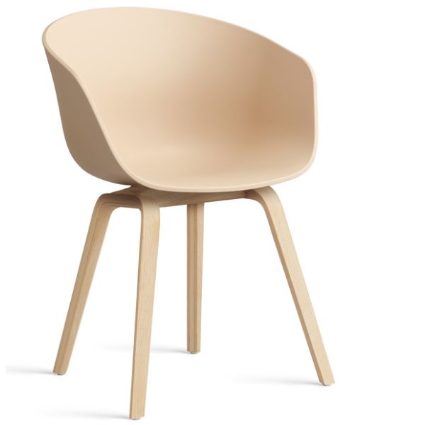 Der About A Chair AAC22 inkl.. Filzgleiter (pale beach) zeichnet sich durch einen modernen, beigefarbenen, gebogenen Kunststoffsitz und helle Holzbeine aus, inspiriert durch das ikonische Design von HAY, das vor einem weißen Hintergrund gezeigt wird.