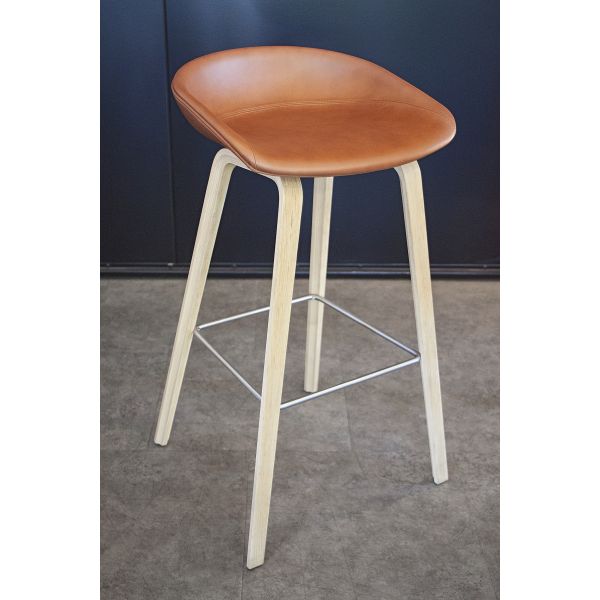 Der About A Stool AAS33 Leder (Sitzhöhe: 74 cm) second hand (cognac) bietet mit seinem cognacfarbenen Ledersitz, den hellen Holzbeinen und der Metallfußstütze ein stilvolles und modernes Barhockerdesign.