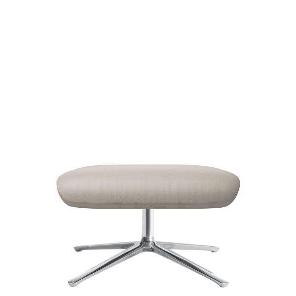 Der CORDIA Hocker (zementgrau 281) zeichnet sich durch ein modernes beigefarbenes Lederdesign mit einem verchromten X-förmigen Sockel aus, der auf weißem Hintergrund zu sehen ist.